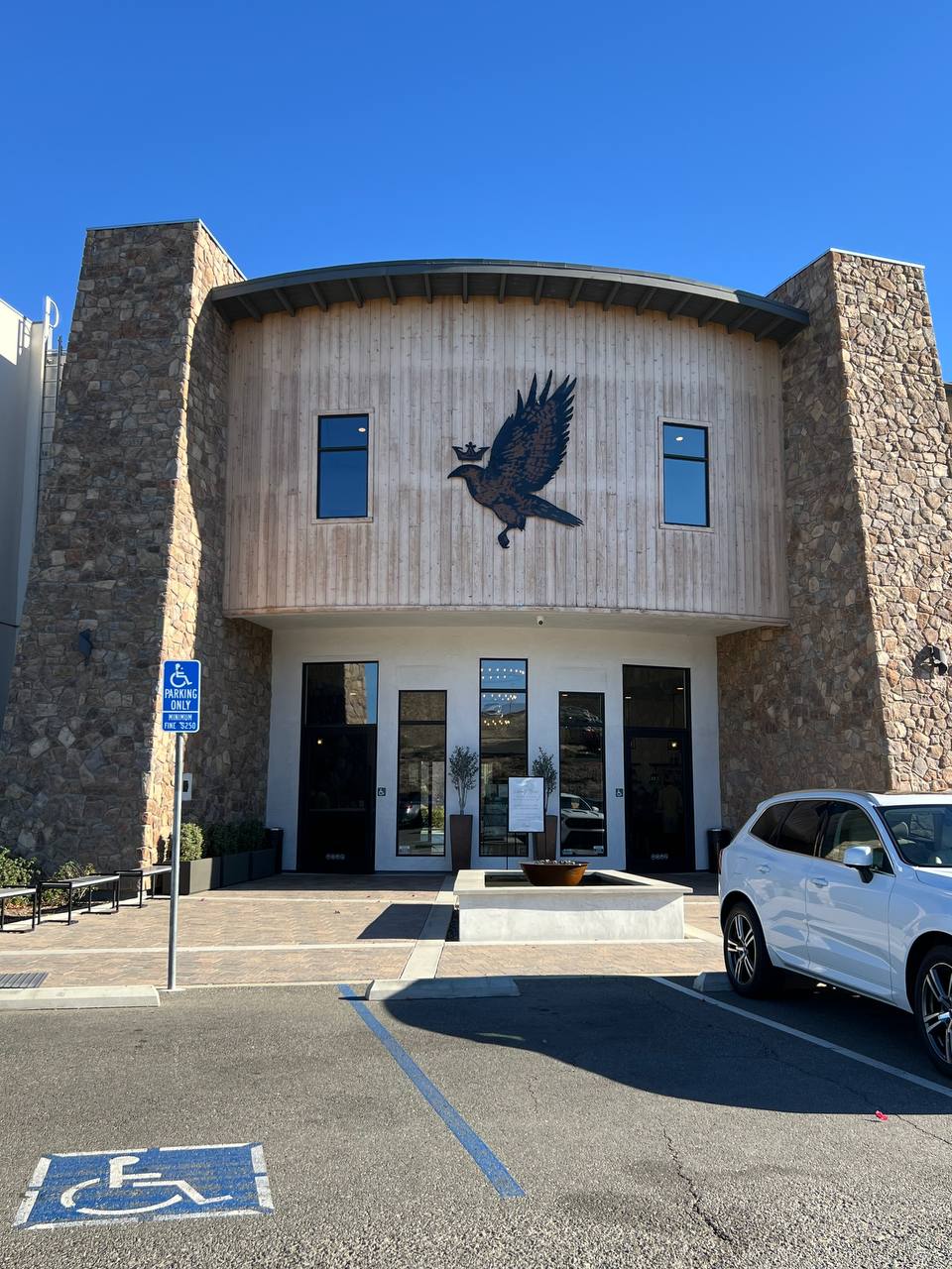 Altísima Winery tasting room, stone and wood, with the crowned bird above the entrance